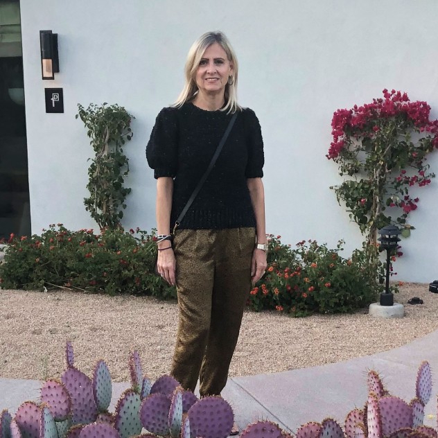 Debra posing outside of a building surround by tropical plants.