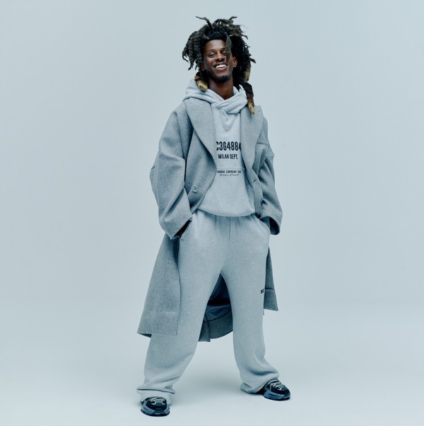 A male model wearing a grey overcoat over a sweatsuit.