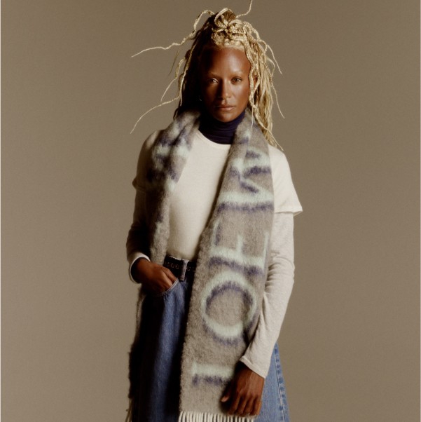 A female model wearing an oversized scarf over a sweater.