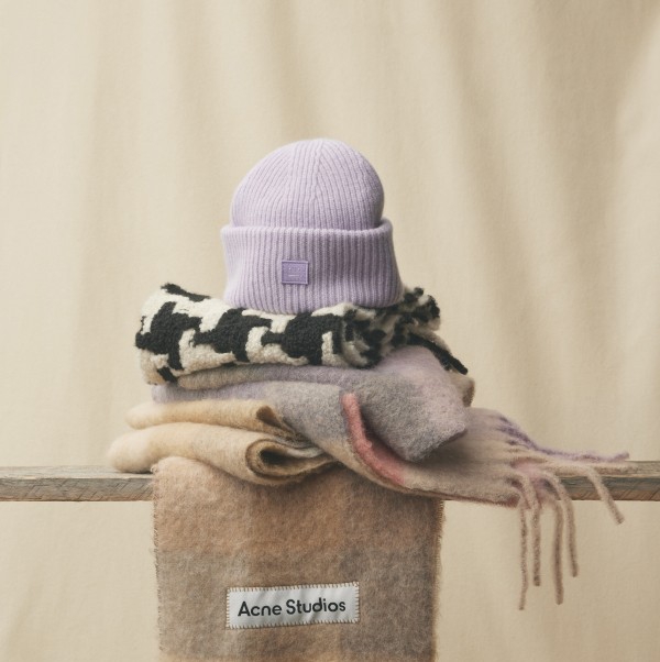 A purple toque on top of a pile of differently patterned scarves.