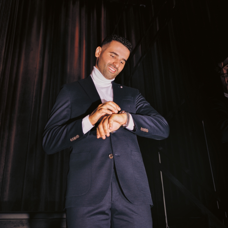 Nazem Kadri wearing a navy suit and white turtleneck, looking down.