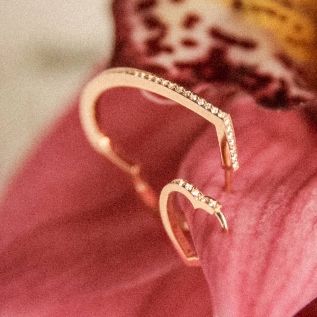 Two heart shaped earrings pinned to a cushion