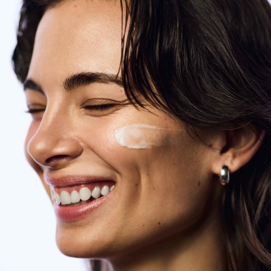 A smiling model with a smear of cream on her cheek