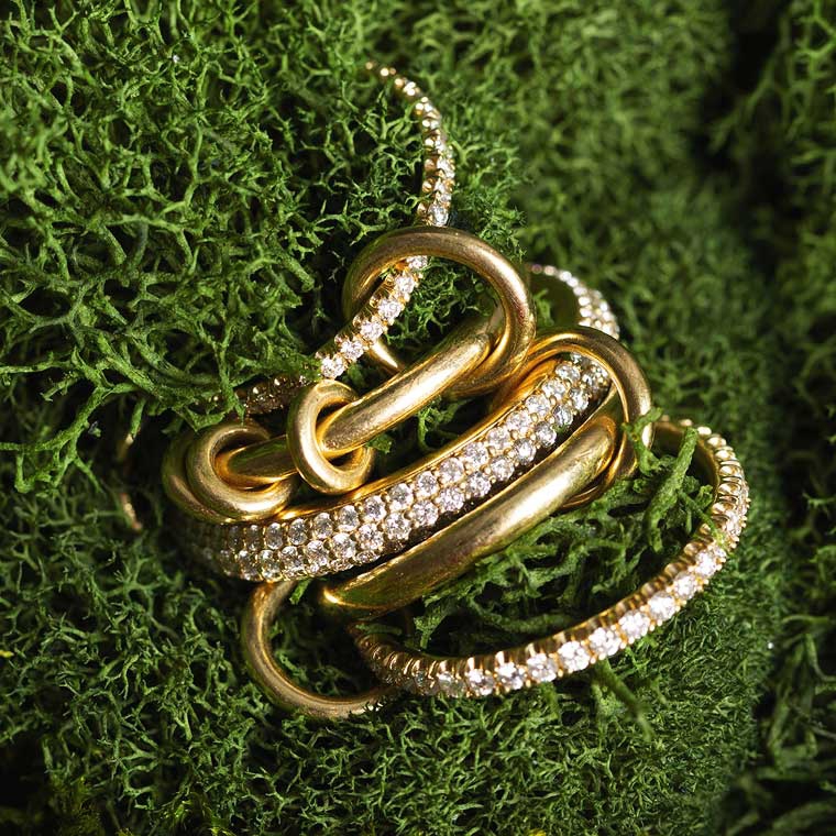 Two heart-shaped pieces of jewellery, styled next to a pink flower.