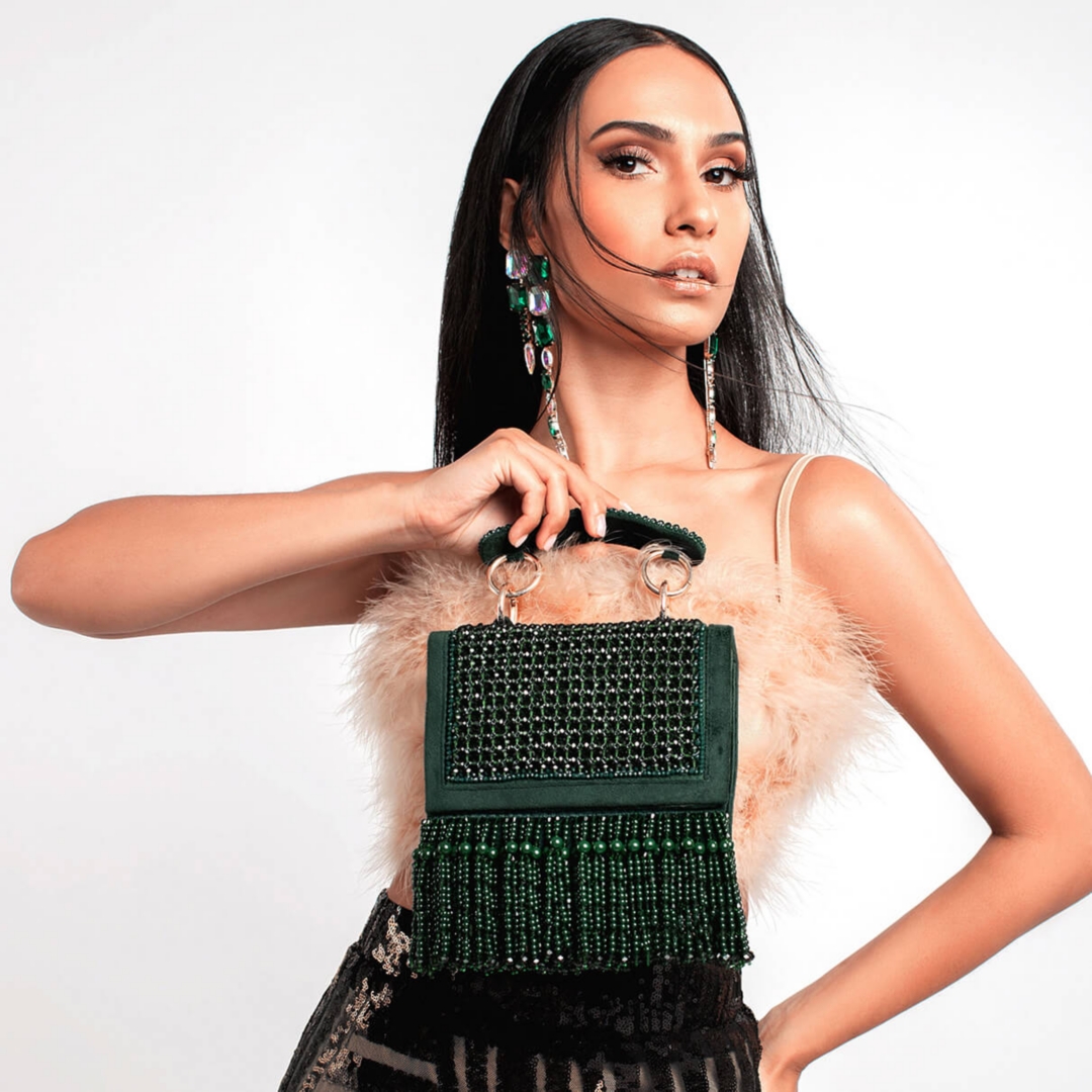 Model posing with a dark green, beaded clutch