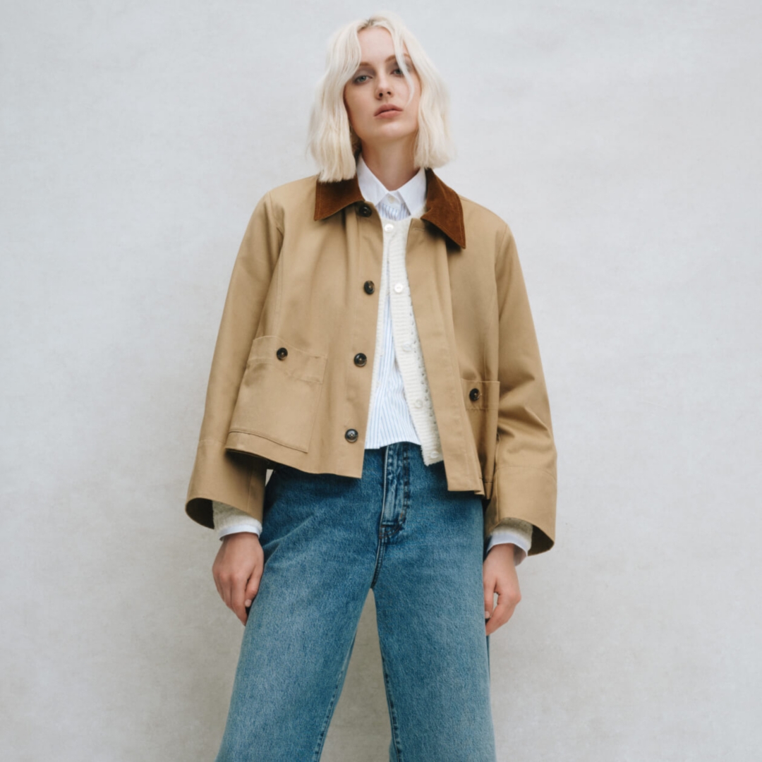 A model posing in a tan chore coat and blue jeans