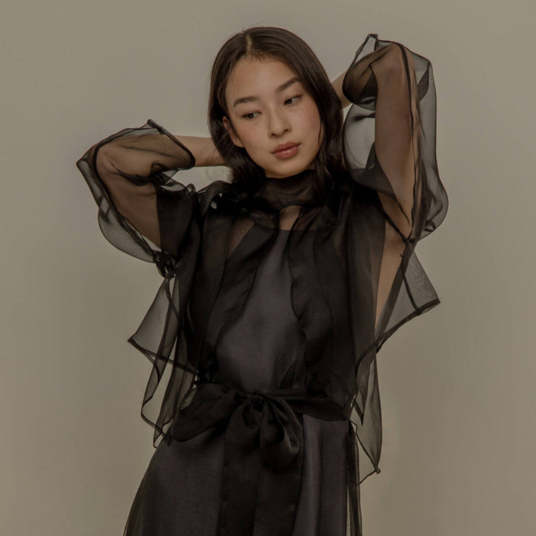 A model posing in a sheer black dress